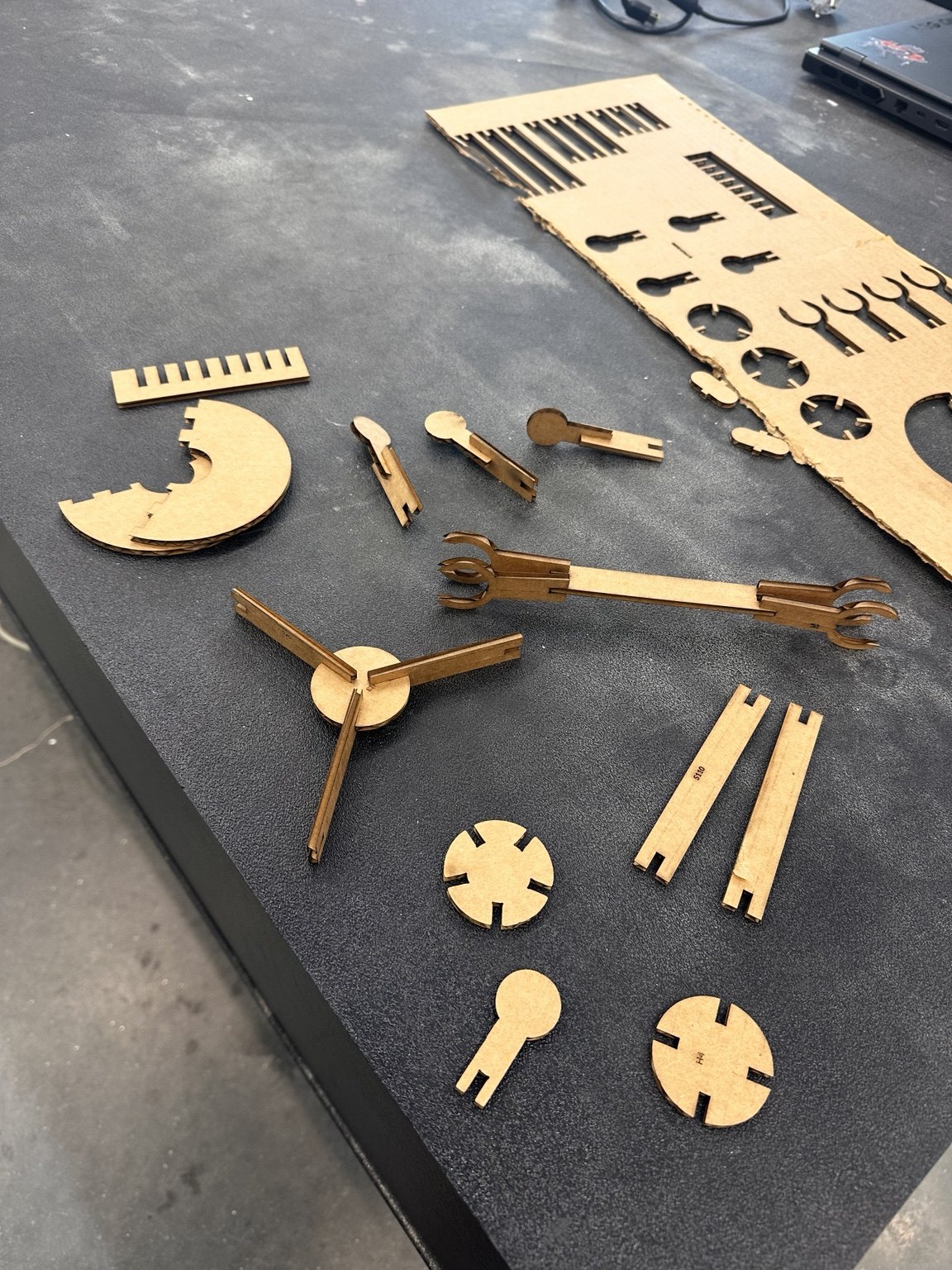 Laser-cut press-fit test comb and several cardboard kit pieces on the shop table