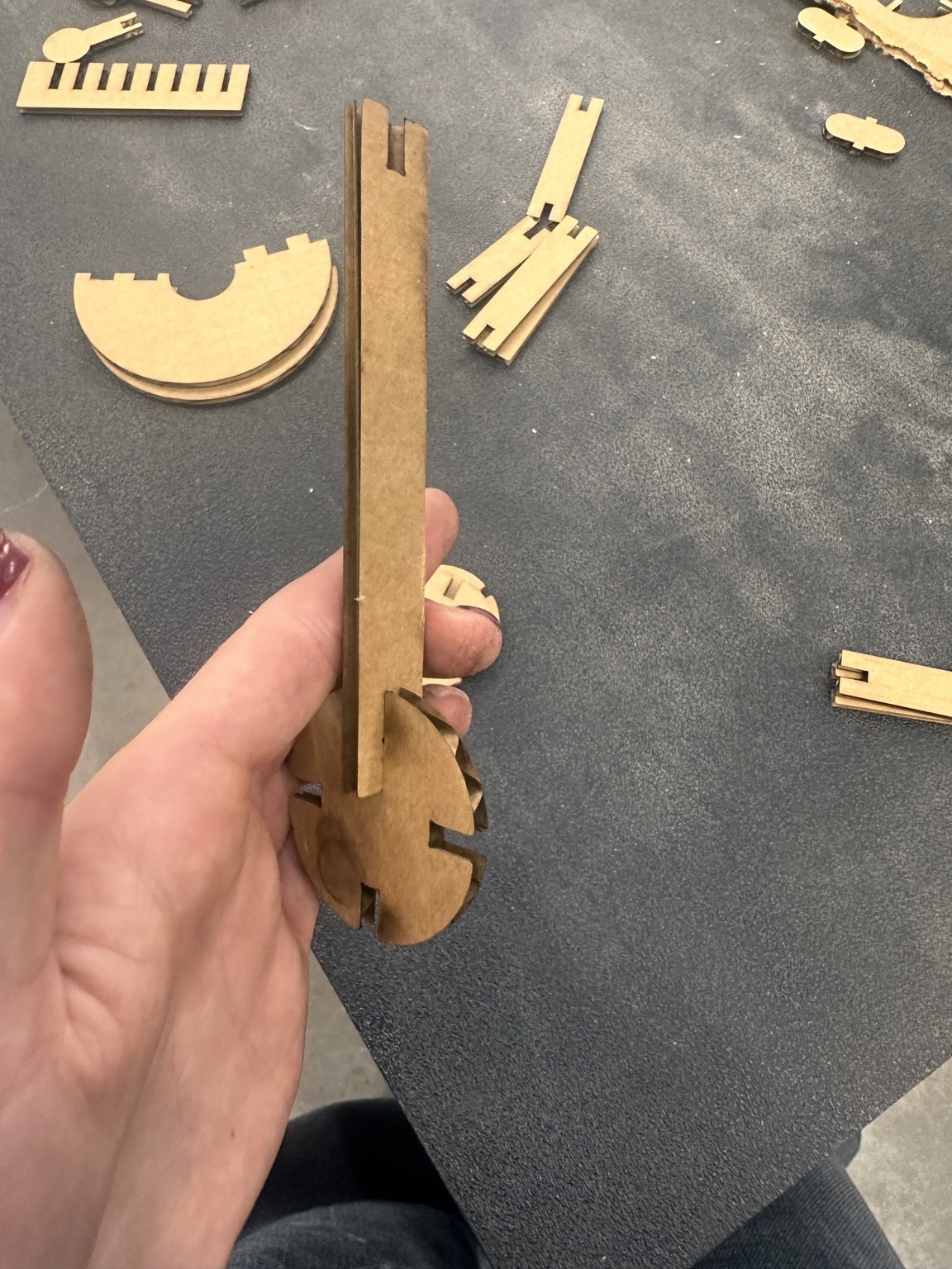 Hand holding a cardboard joint prototype with a slotted bar