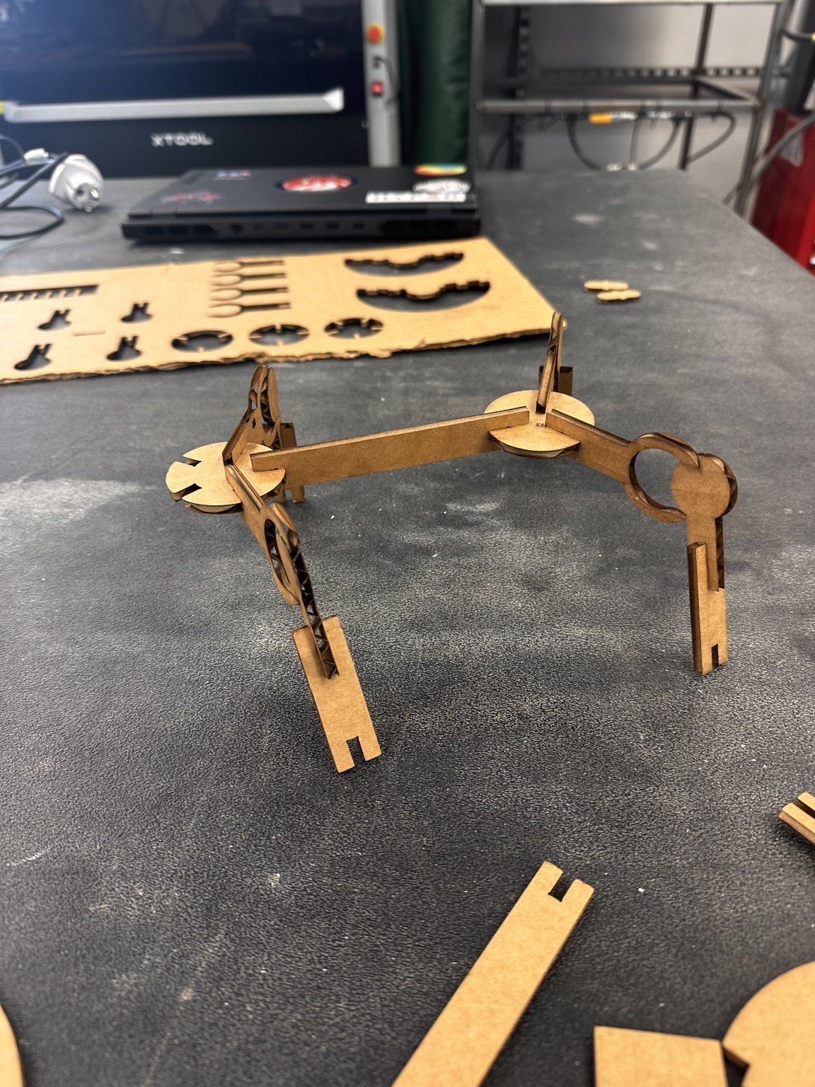 Partially assembled cardboard robot on a workbench beside the laser-cut parts