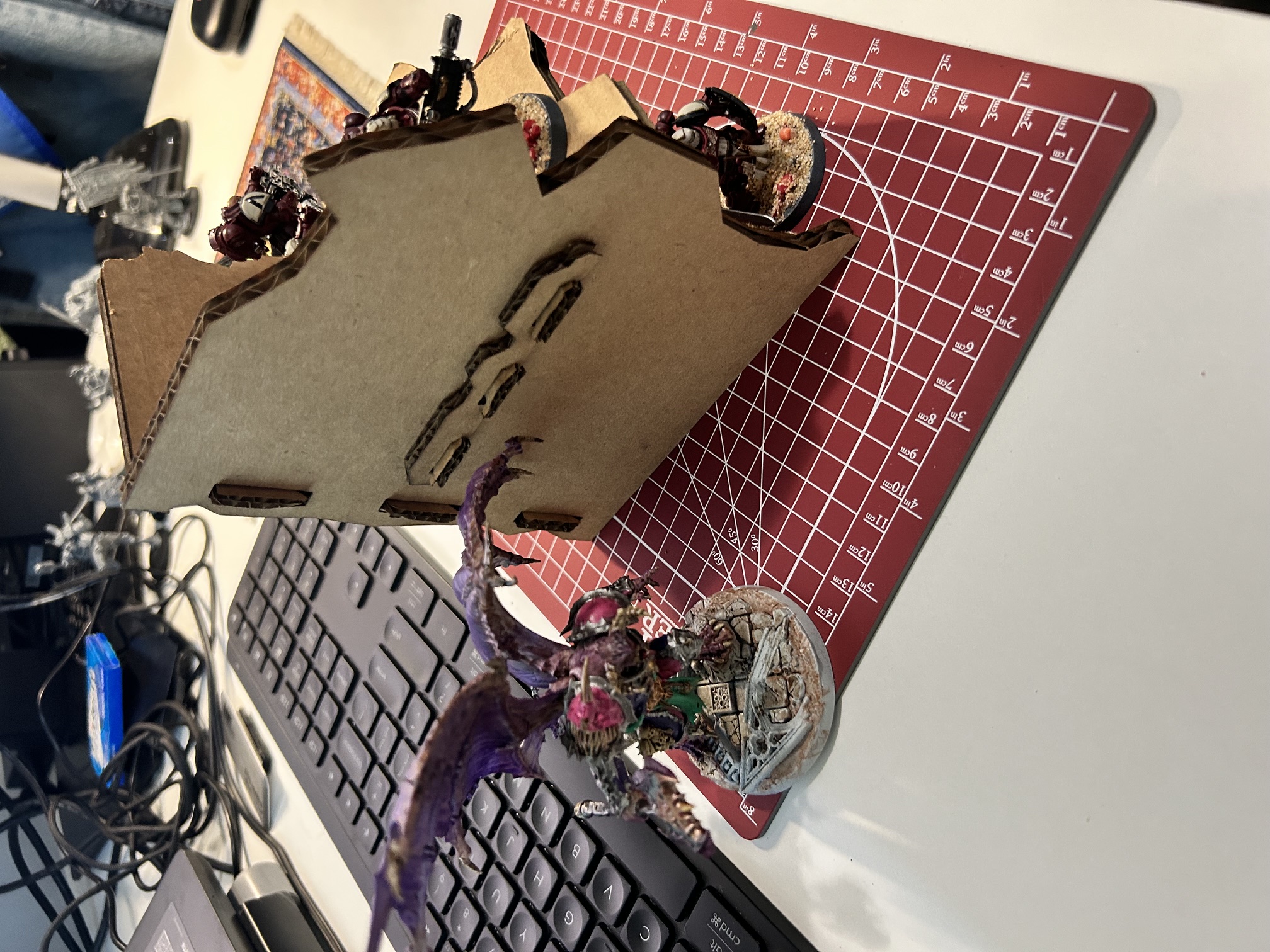 Side view of the assembled terrain showing the tab slots cut through the wall, with painted models alongside for scale