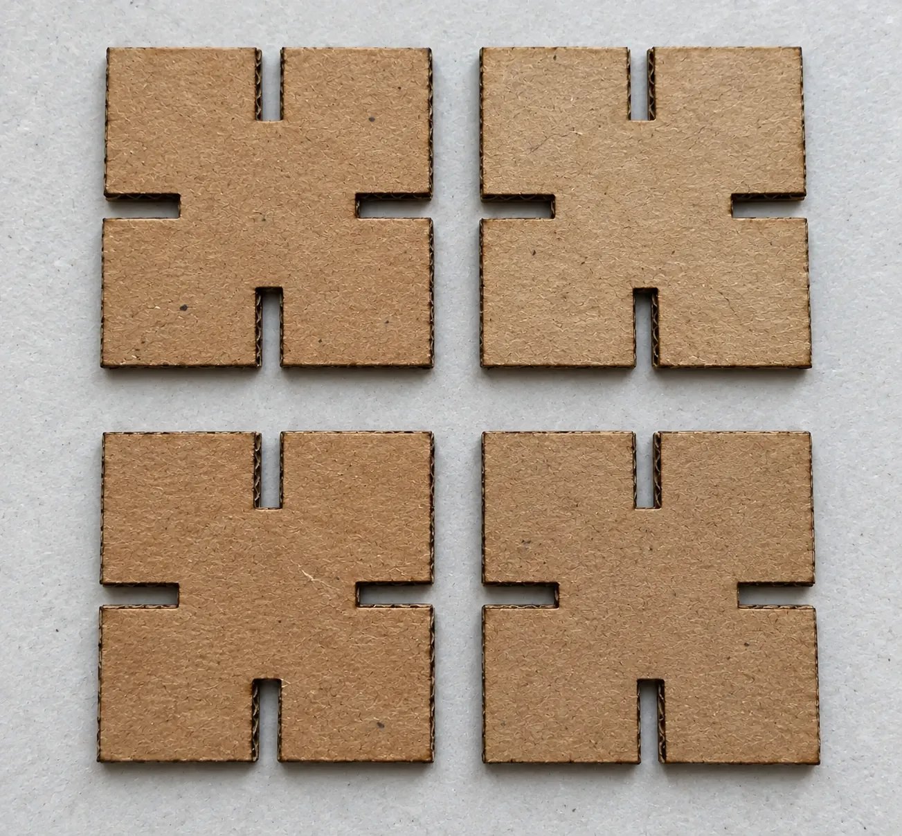 Four square cardboard tiles, each with four centered edge slots, matching the r1 layout