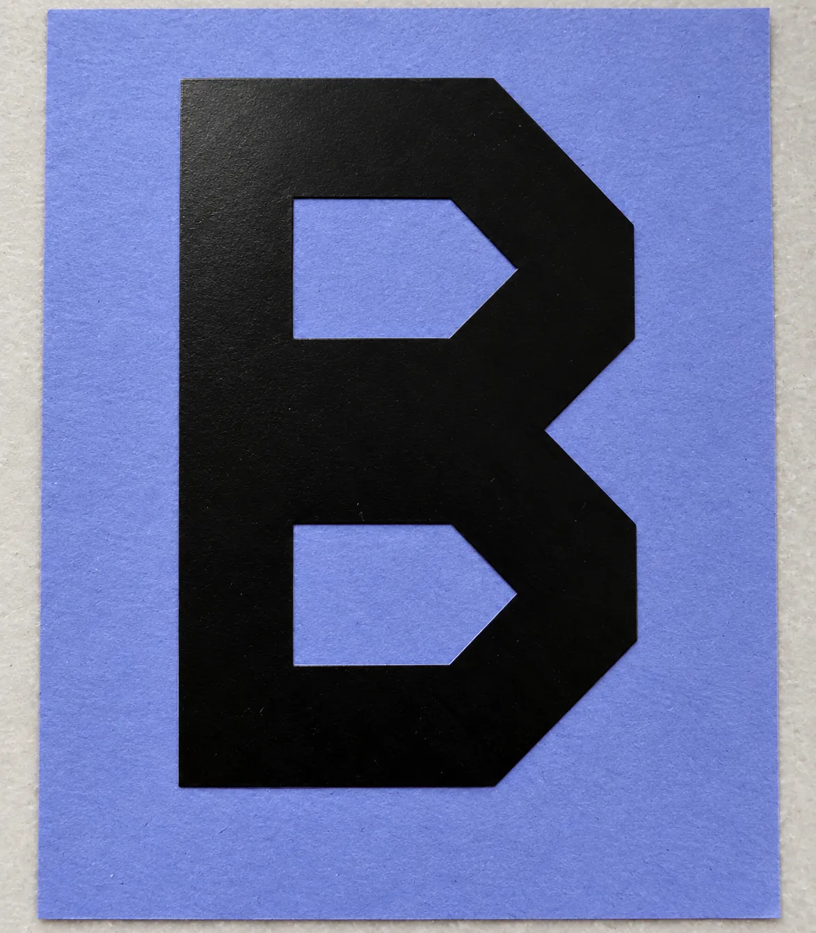 Black angular B vinyl decal with two openings on blue-violet release paper