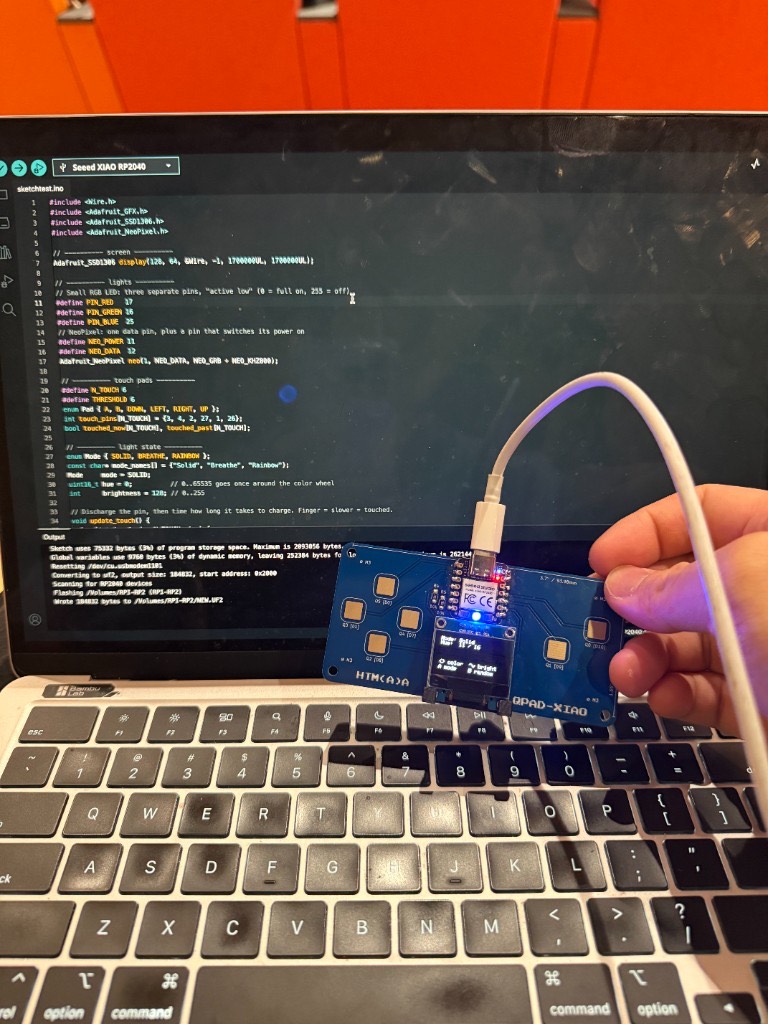 Assembled QPAD-XIAO board plugged into a laptop running Arduino code for the RP2040