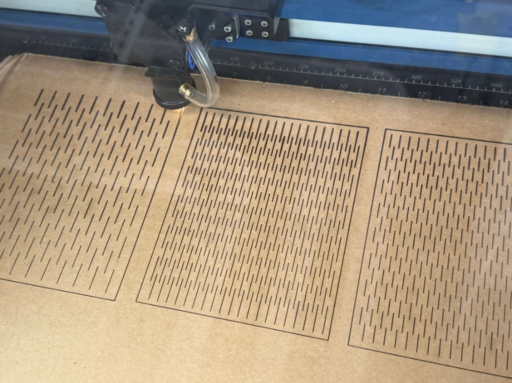 Laser cutter engraving living hinge patterns into cardboard