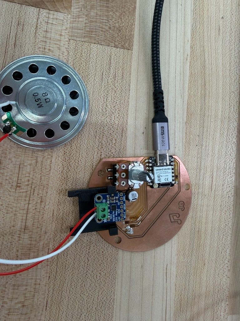 Assembled circular board connected to the speaker and a USB cable, with the XIAO, amplifier, potentiometer, and capacitor on it