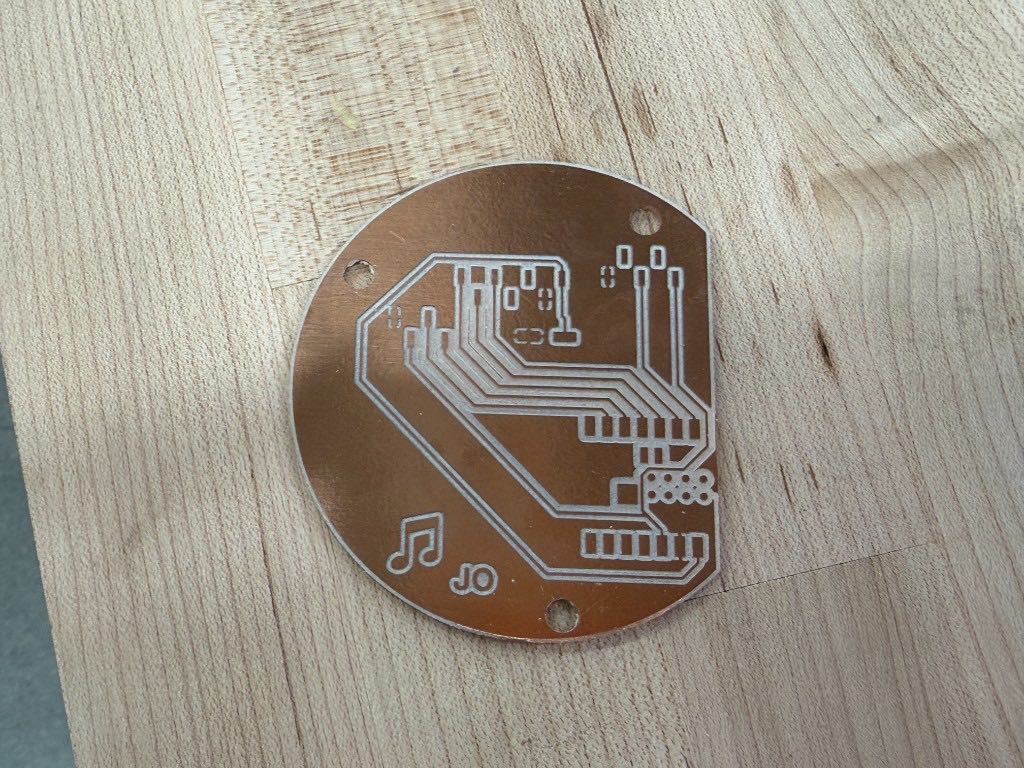 Milled circular copper board with silver traces on a wood table