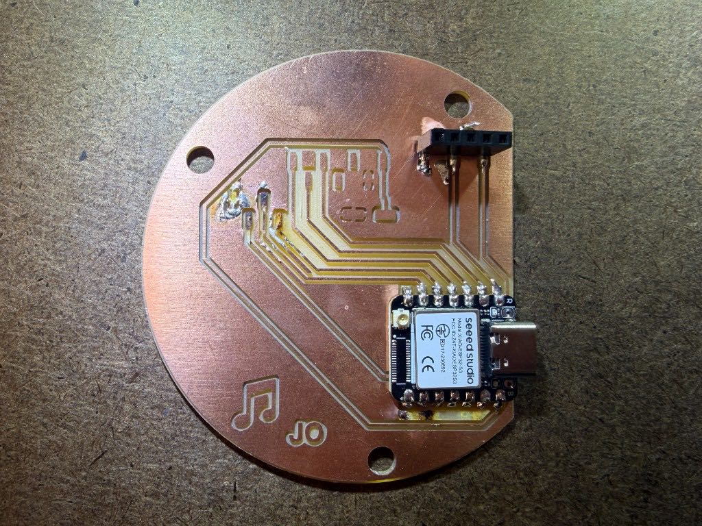 Circular copper board with the XIAO soldered on and a black pin header