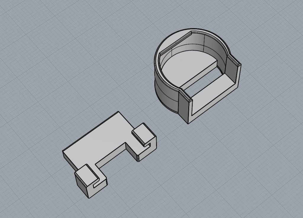 3D model of a circular enclosure and a flat bracket piece on a grid