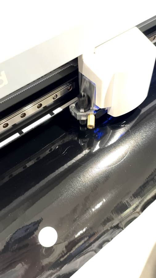 The GX-24 blade cutting the badge into black vinyl