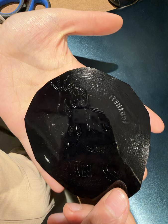 The cut piece of black vinyl held in a hand before weeding