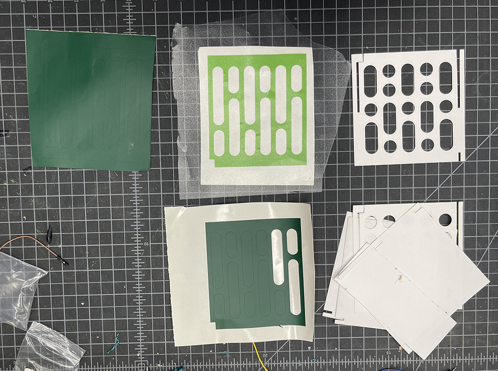 Aligning vinyl stickers on the paper plates with transfer tape.