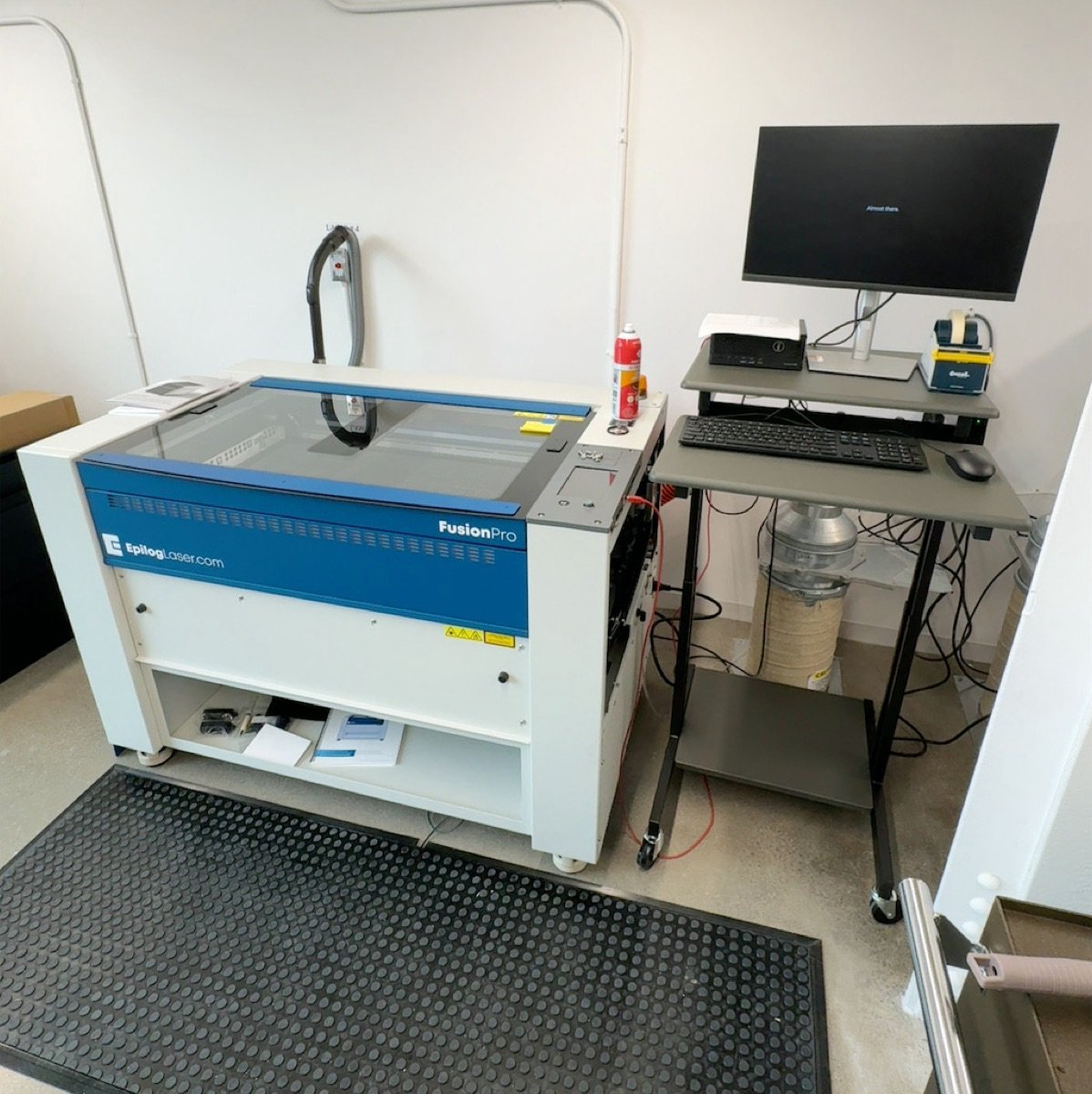 Epilog Fusion Pro laser cutter with its Rhino workstation and pressure mat