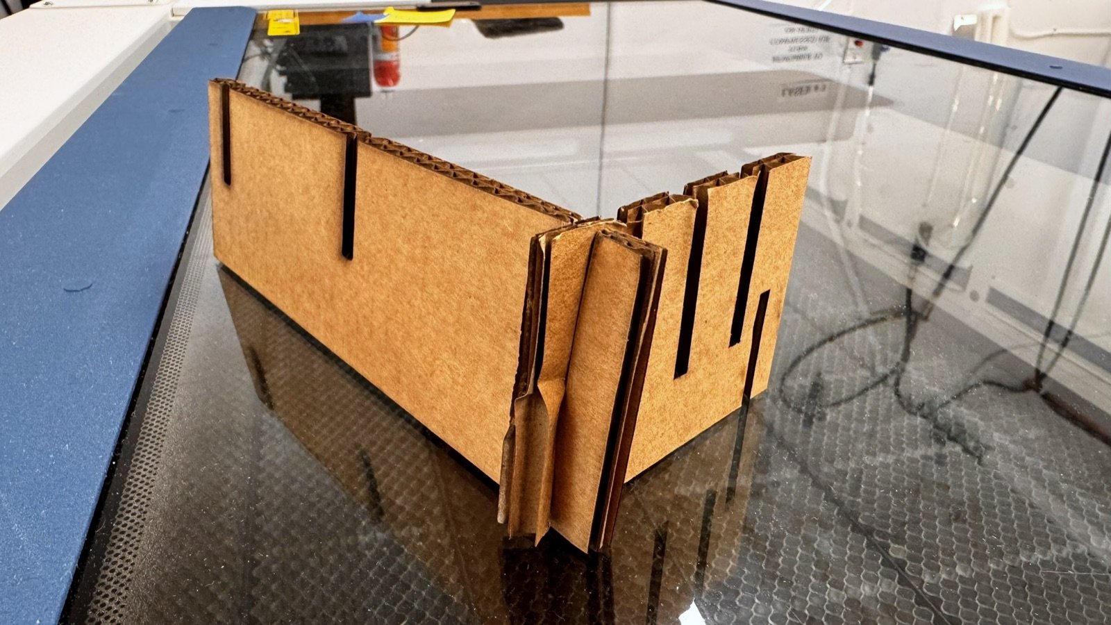 Half-assembled cardboard stand with crushed, torn slot joints