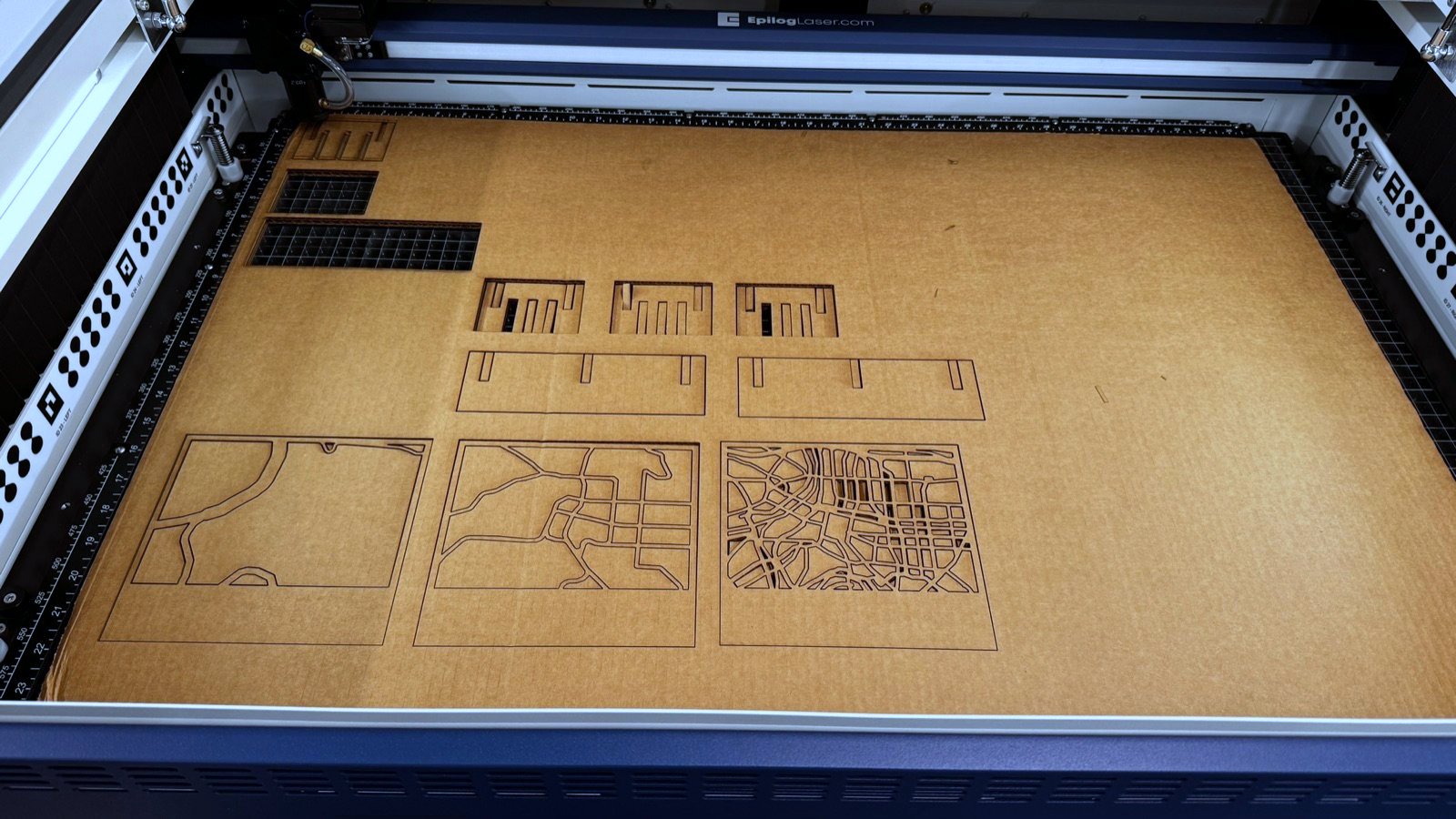 Full cardboard sheet on the laser bed with map plates, ribs and rails cut out