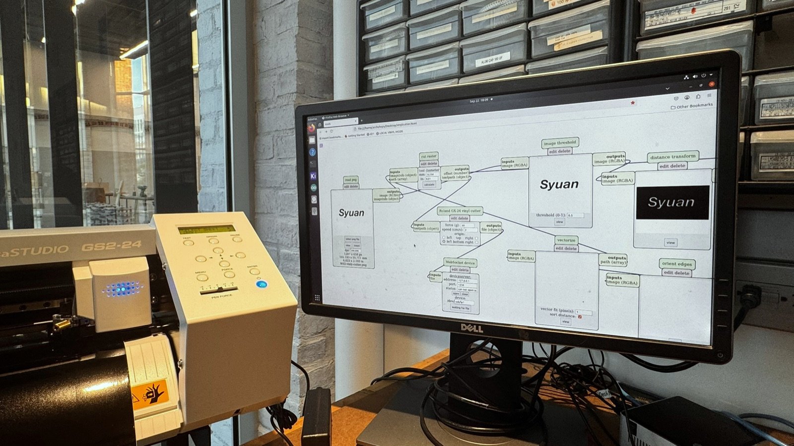 Vinyl cutter beside a monitor showing the cutting software with the name artwork