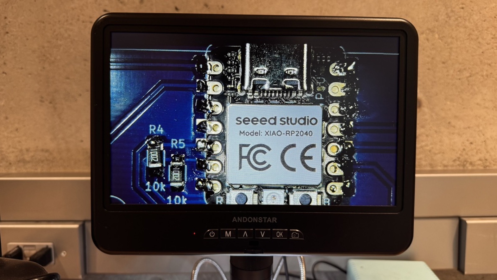 Seeed Studio XIAO RP2040 under the microscope, next to two 10k resistors