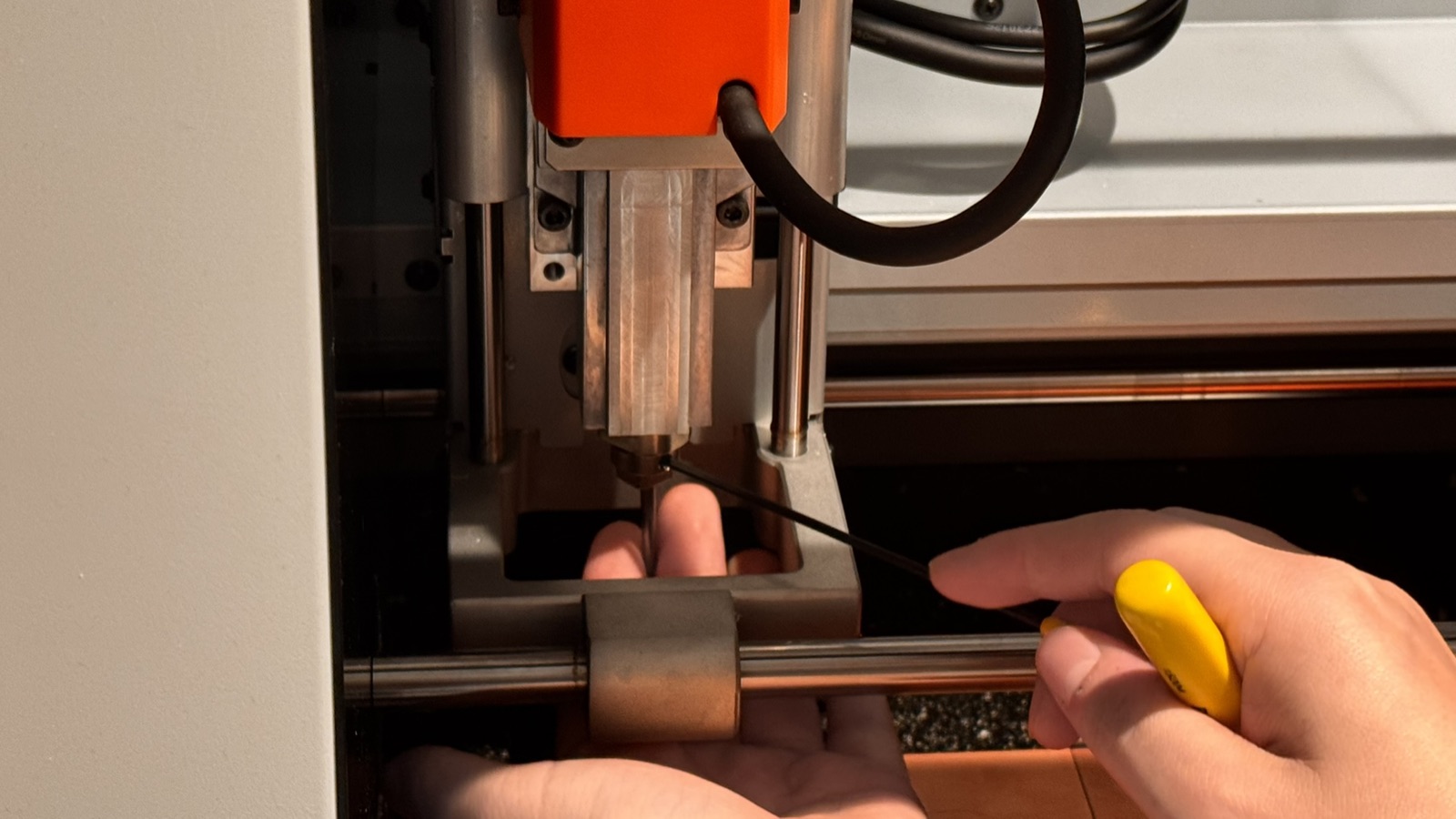 Hands changing the end mill in the milling machine with a hex key