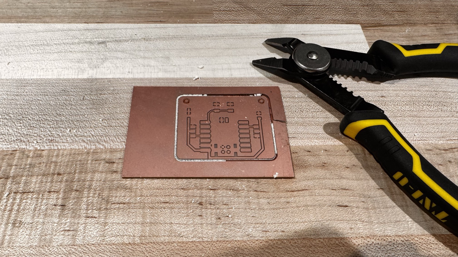 The latest version 2 board on a wooden bench with a pair of cutters beside it, after the surrounding stock was removed