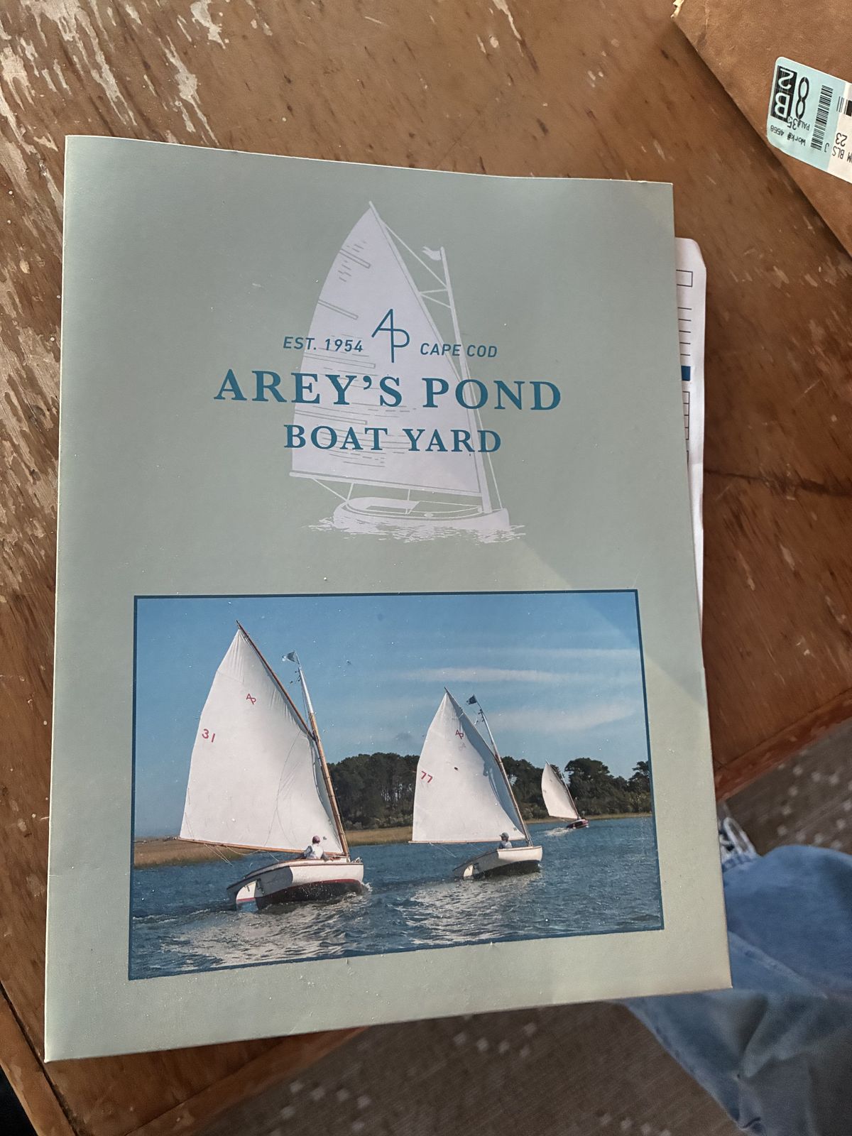 Arey's Pond Boat Yard leaflet from the Pavilion archives, with the yard's sail logo, 'Est. 1954, Cape Cod', and a photo of three catboats sailing