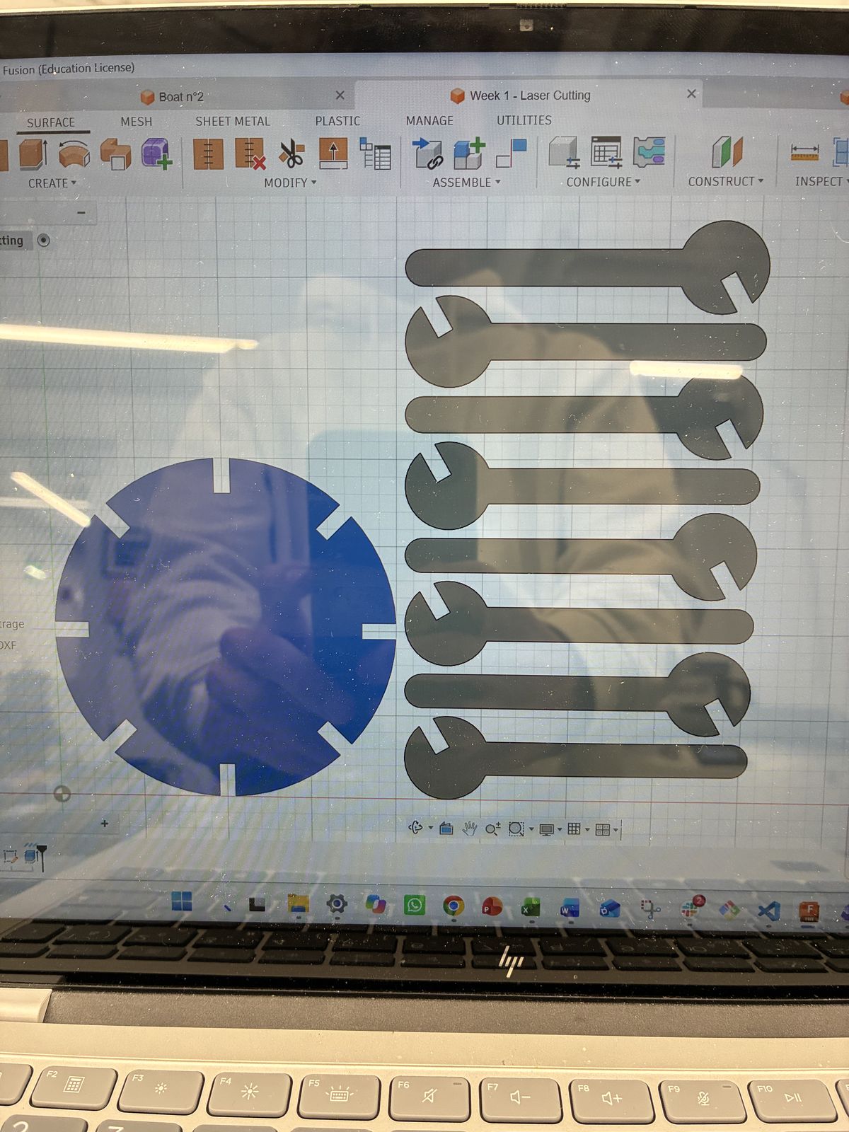 Laptop screen showing the Fusion 2D sketch: a notched circular disc on the left and eight identical branch profiles laid out side by side on the right