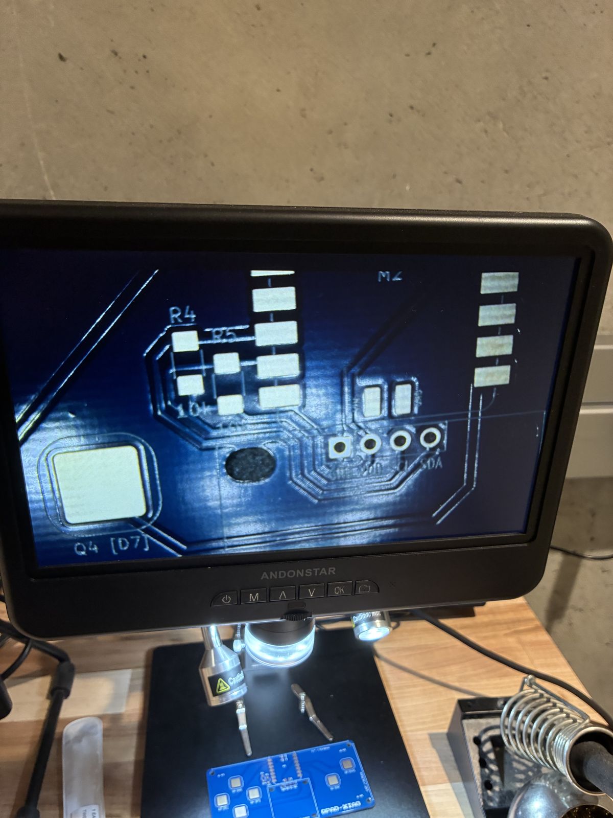 Digital microscope screen showing a bare blue circuit board close-up, with the empty R4 and R5 resistor pads, a Q4 touch pad and the four OLED header holes labelled GND VCC SCL SDA
