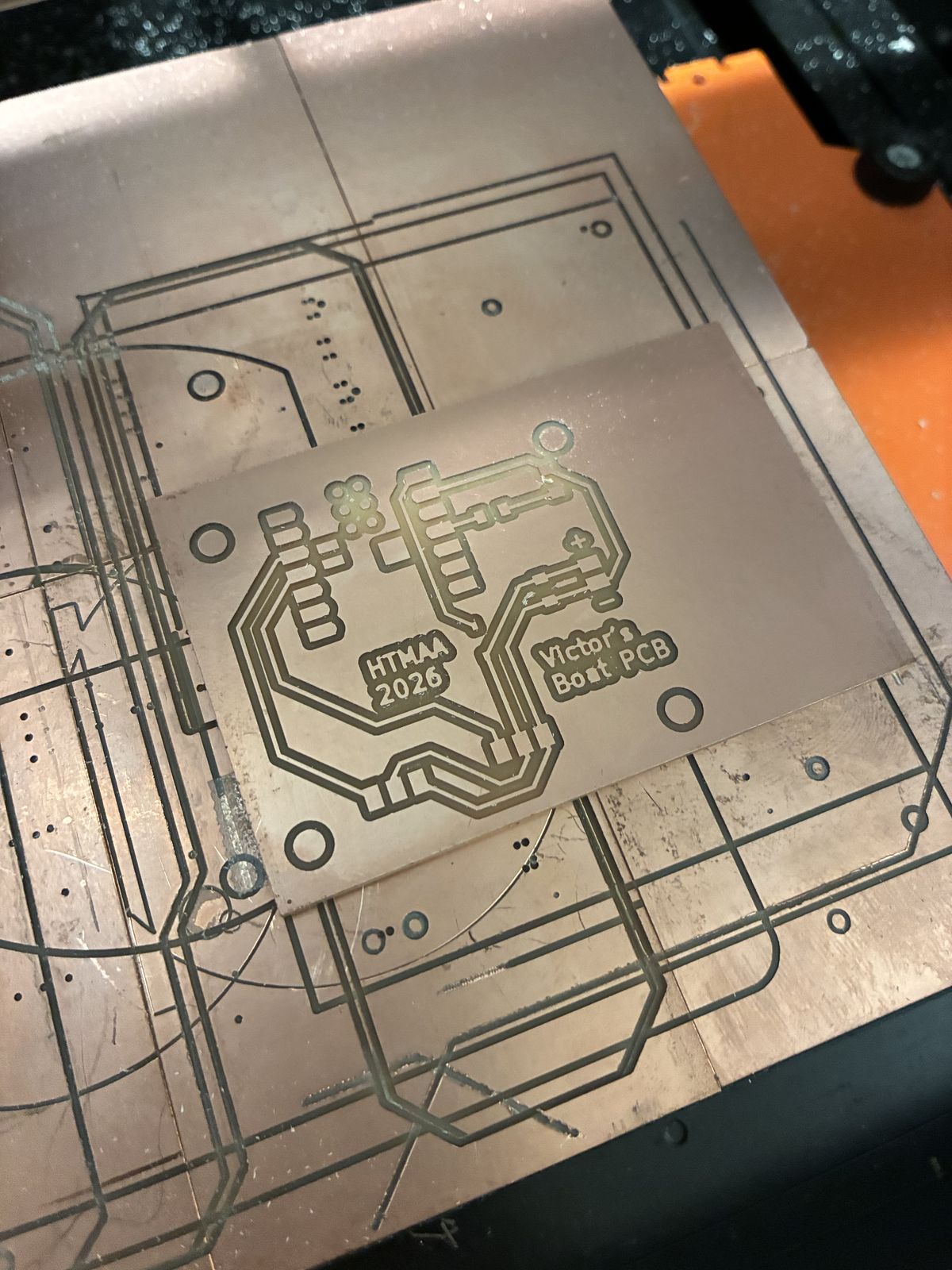 The freshly milled board lying on the sacrificial copper plate of the milling machine, surrounded by the engraved outlines of other students' earlier boards; the tracks, pads and the text HTMAA 2026 and Victor's Boat PCB are clearly engraved