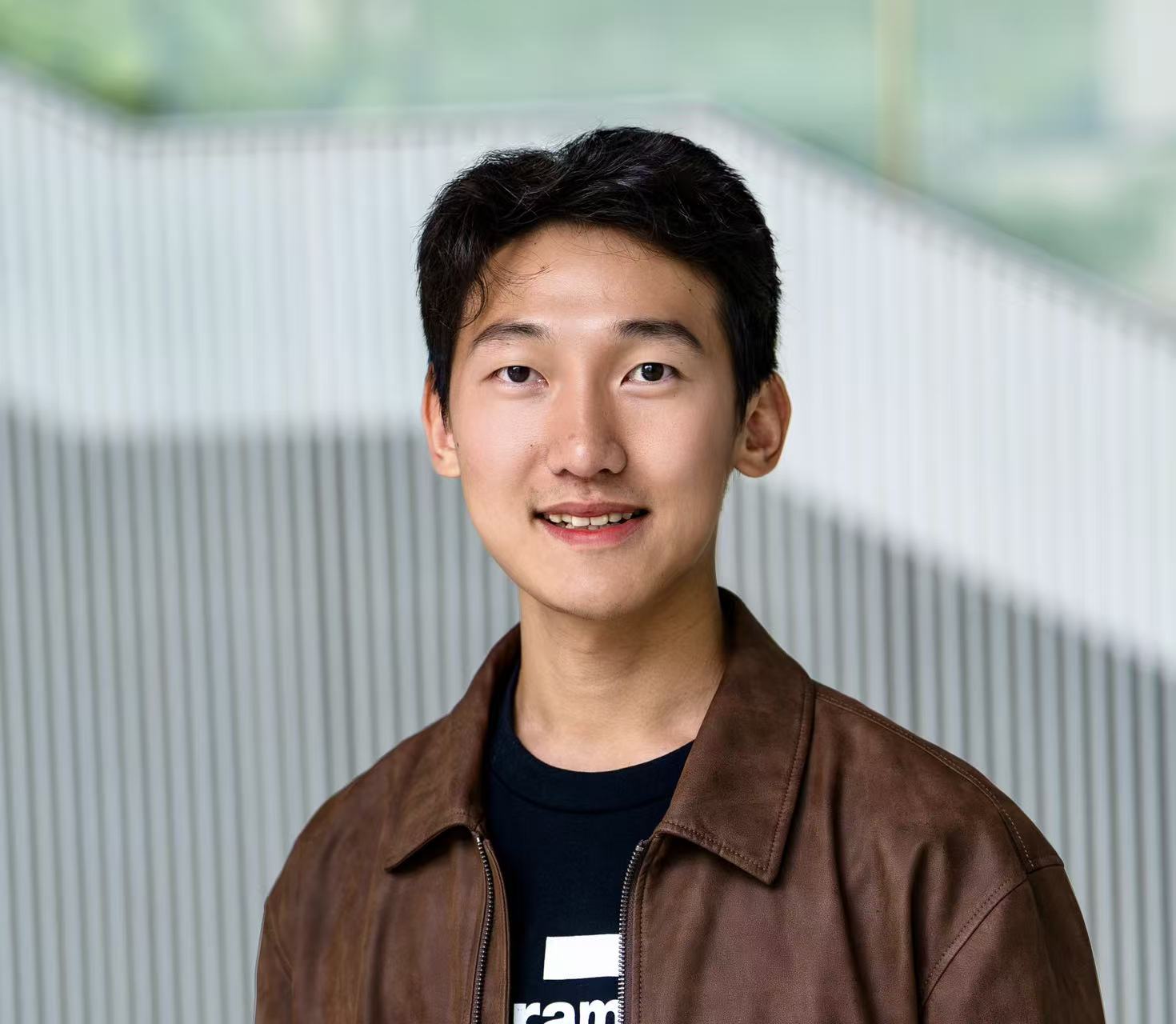 Xiangtao Shi smiling in a brown jacket