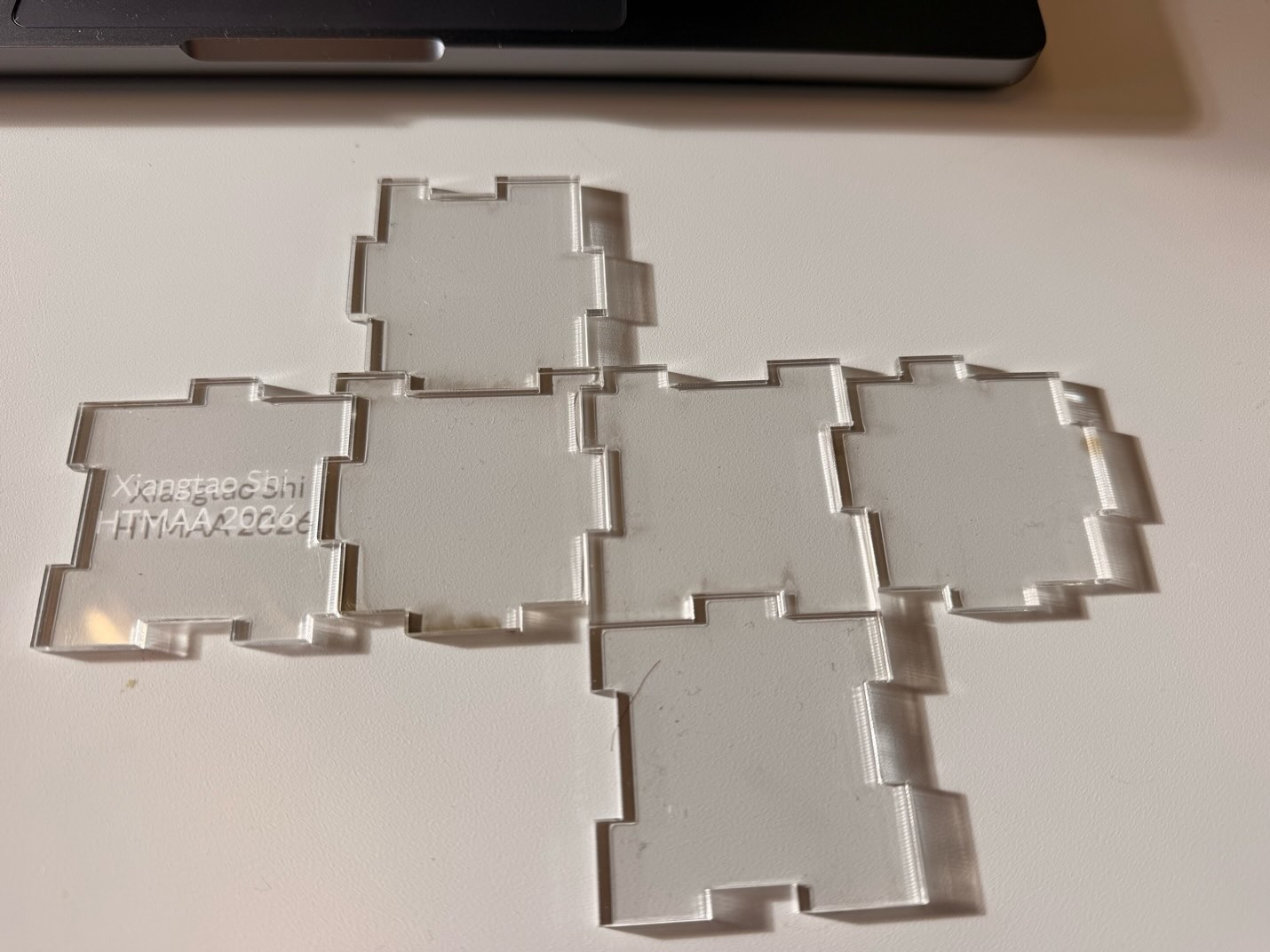 Clear acrylic puzzle panels laid out flat, including one engraved with Xiangtao Shi and HTMAA 2026