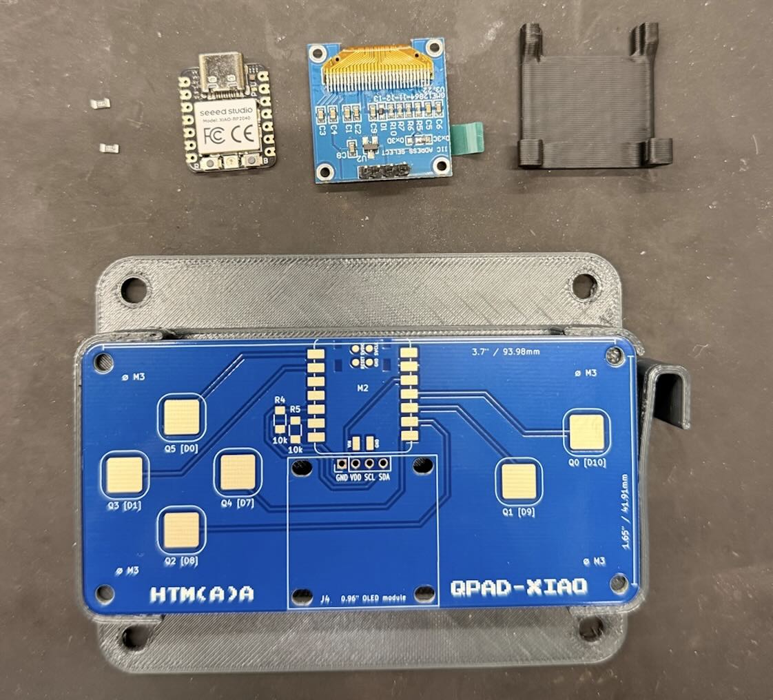 The blue QPad-XIAO board and the small electronic parts arranged on a workbench