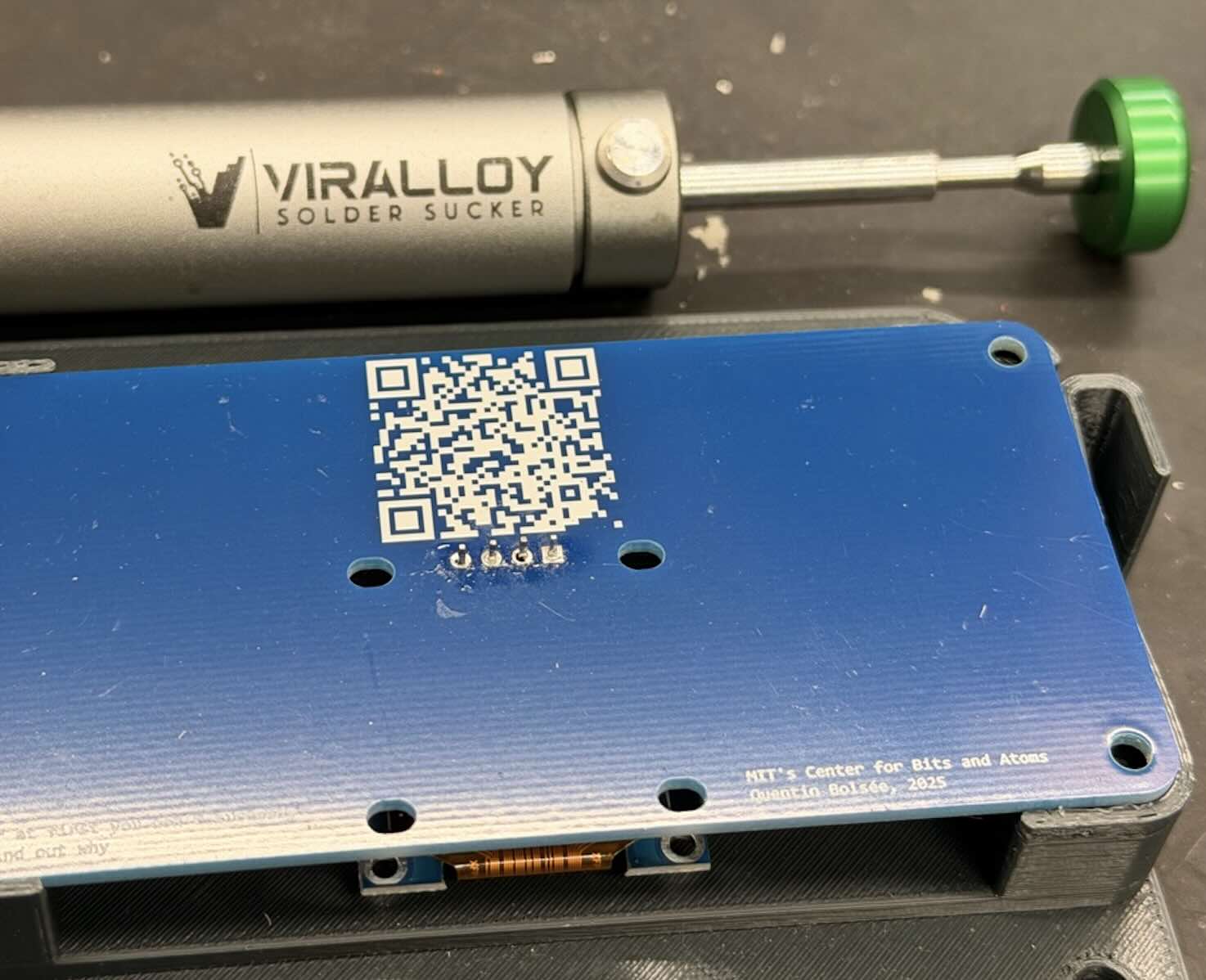 A desoldering pump next to the QPad-XIAO board