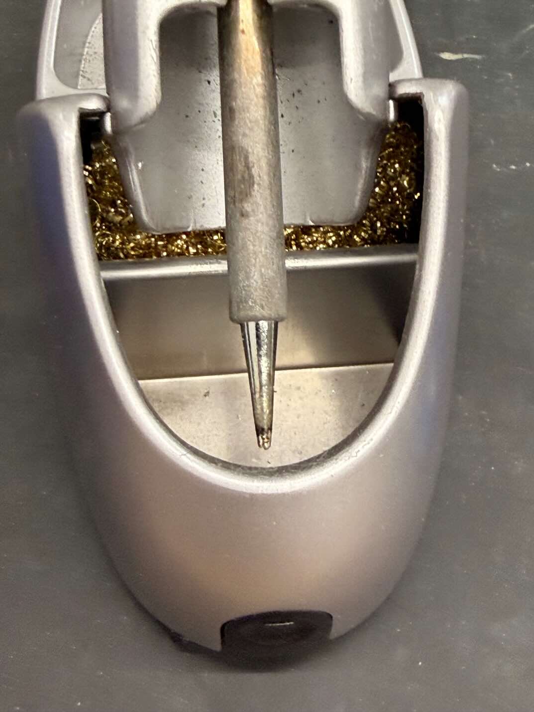 The replacement soldering iron tip in its stand beside brass wool