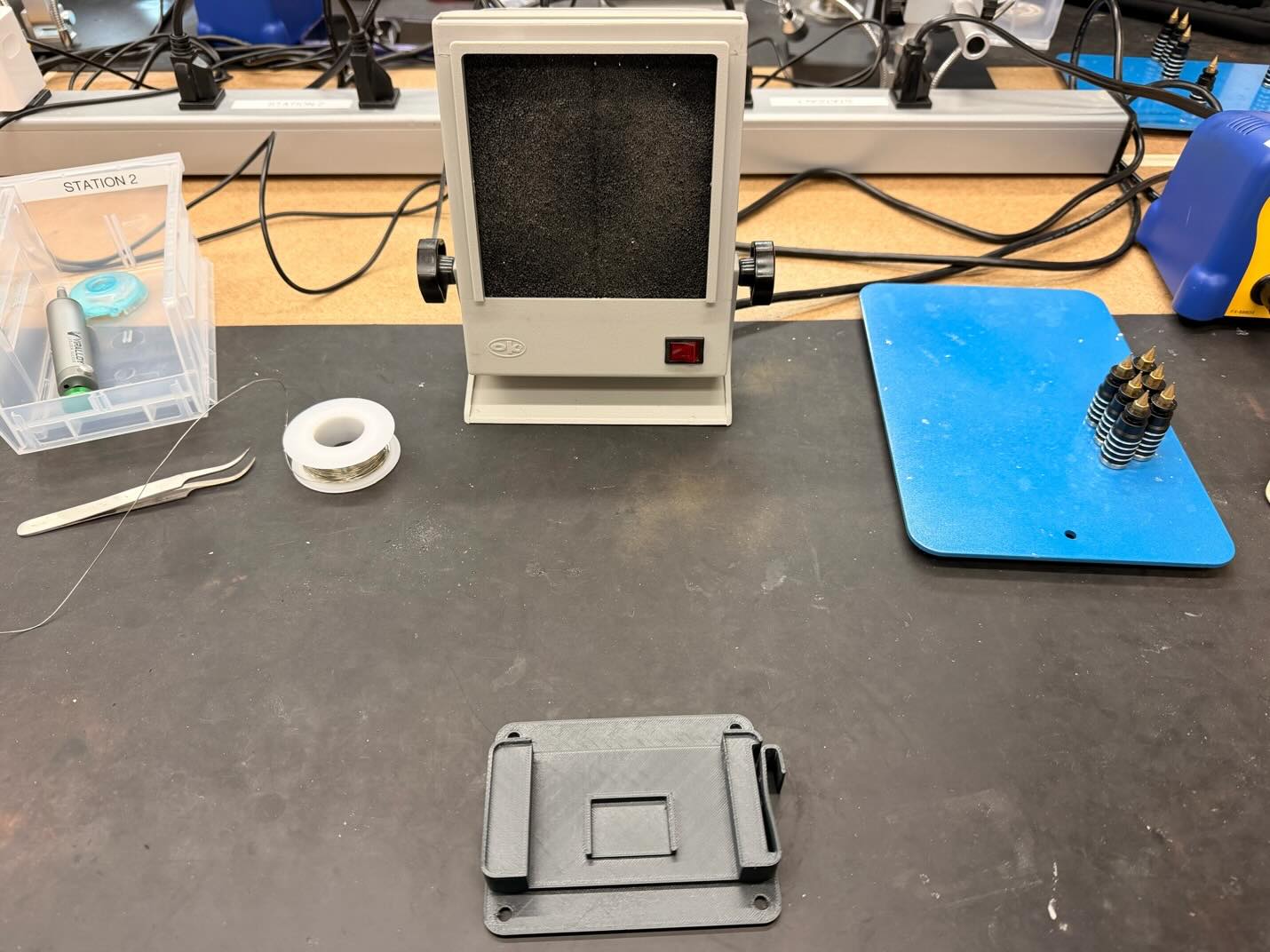 Soldering station, solder wire, and fume extraction hood on a workbench