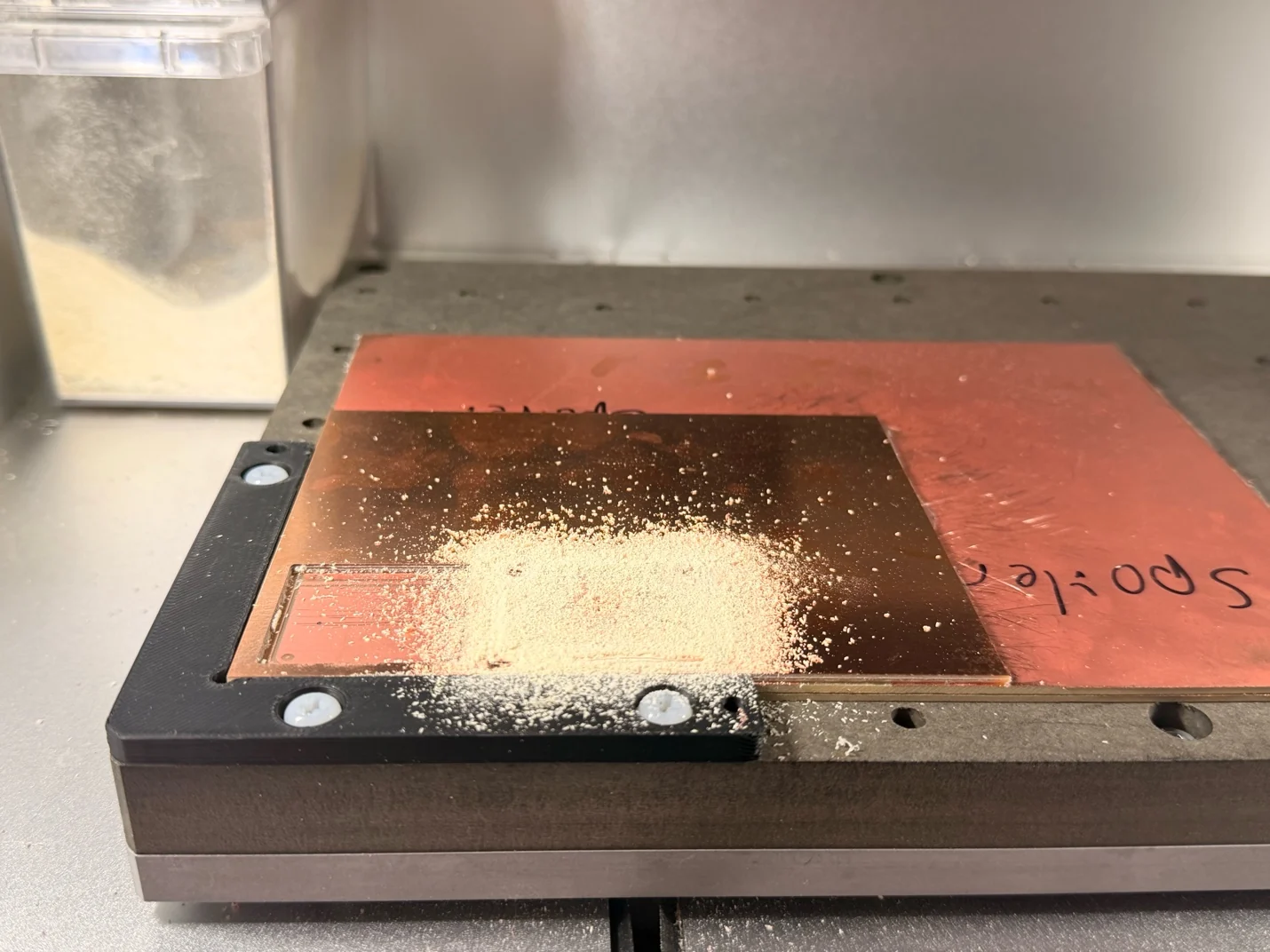 The copper-clad board in the Carvera after milling, with debris still on the surface