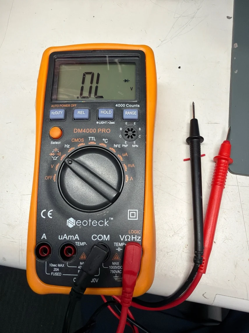 A digital multimeter and probes on the workbench