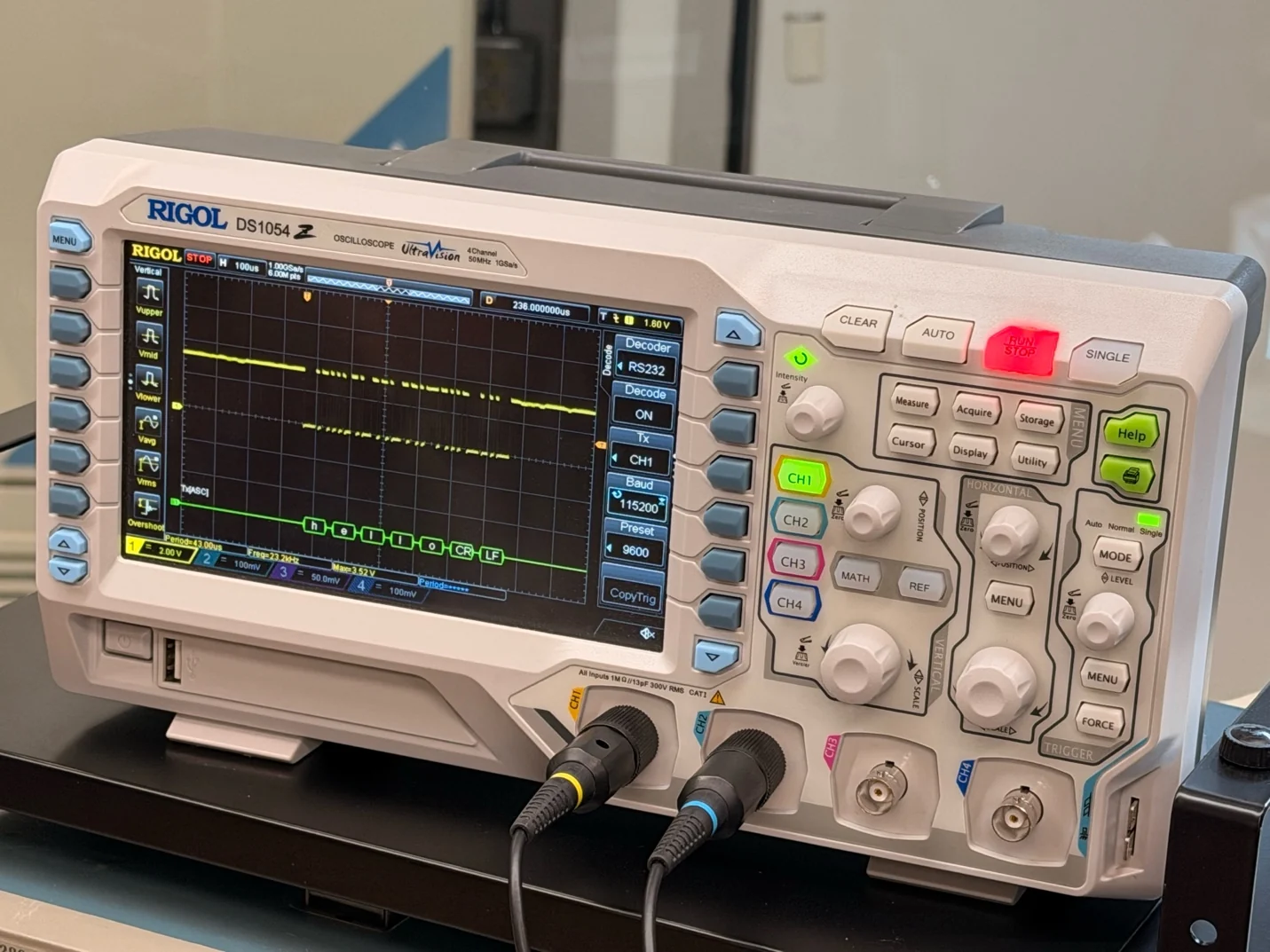 A Rigol oscilloscope displaying a waveform and decoded serial text