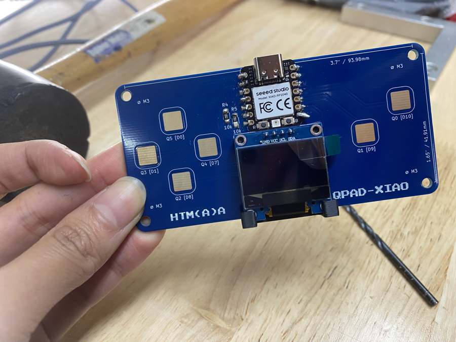 The finished QPad held in my hand, with the XIAO and the OLED soldered on