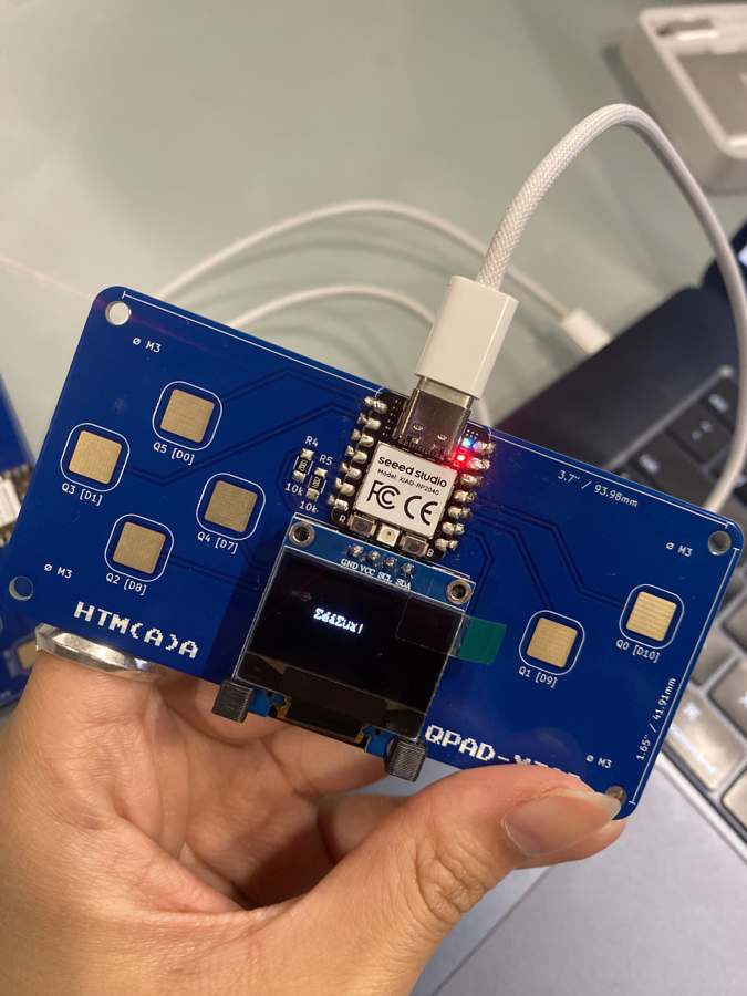 The QPad plugged in over USB-C, with text on the OLED