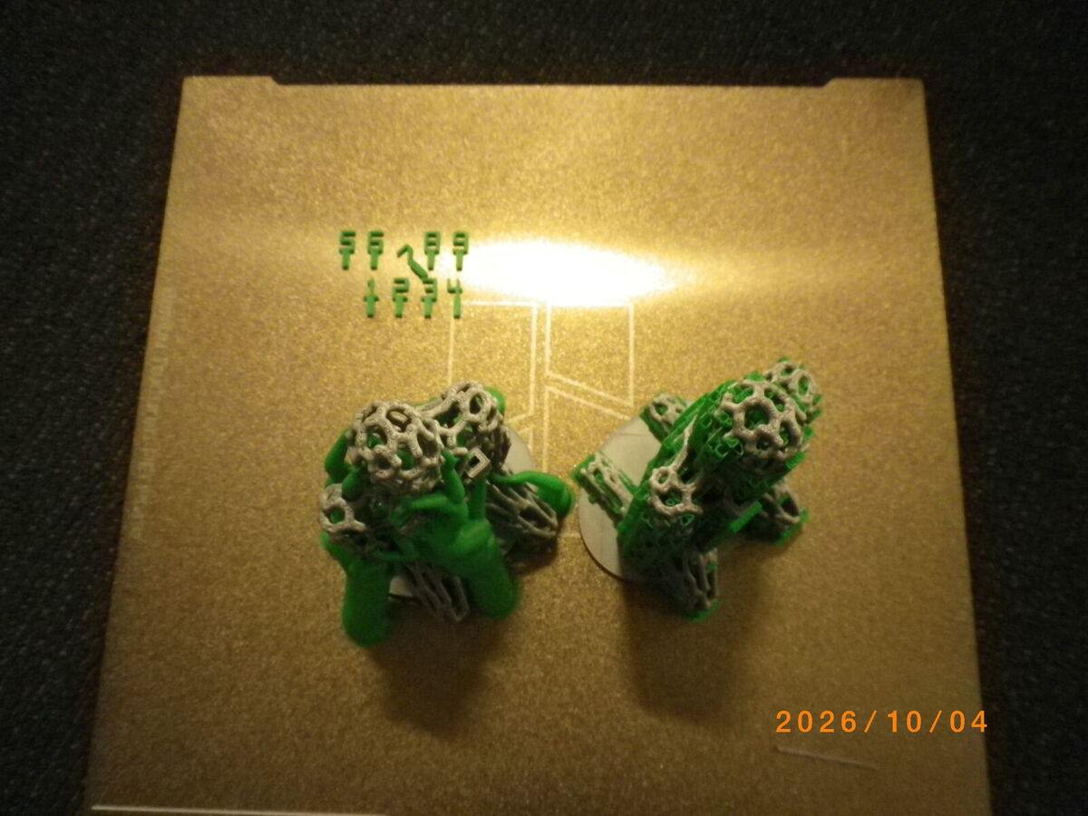 The two figures on the build plate from above, with the small green number panels at the back