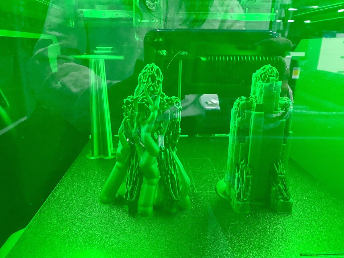 The two figures printing in the Bambu H2S, one in tree supports and one in normal supports