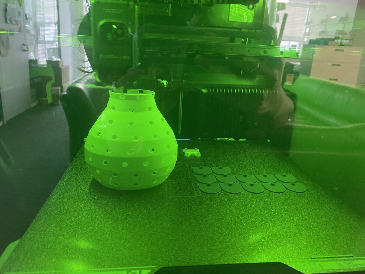 The white mannequin printing inside the Bambu H2S, with purple scales on the plate beside it